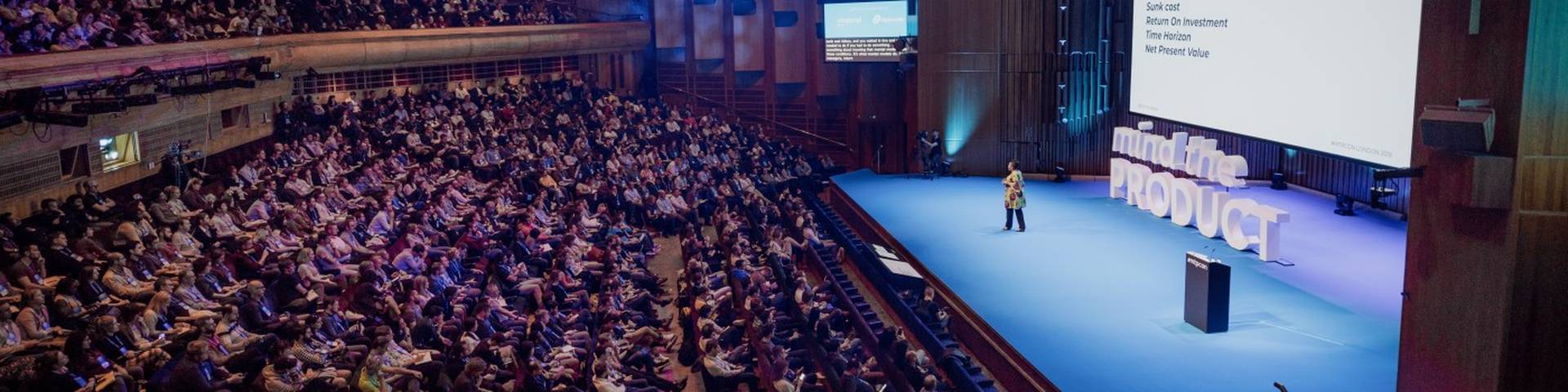 Wide view of Ezinne Udezue on the Mind the Product main stage before a full auditorium